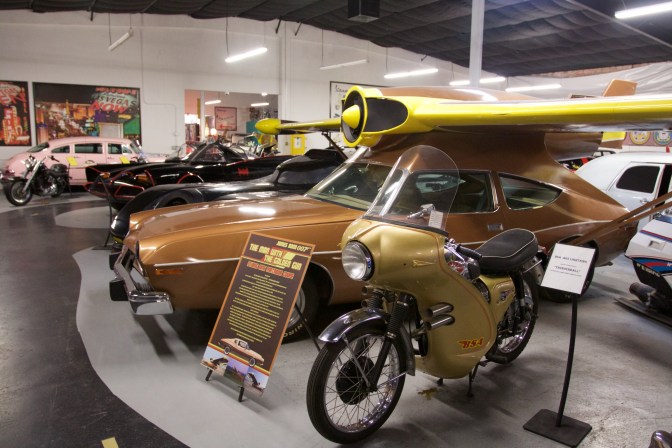 Gold MAC Matador with yellow jet engine and wings on top of vehicle.