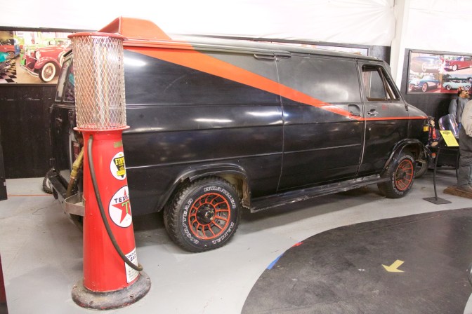 Exterior of black and grey van with orange stripe. A Texaco gas pump is in the foreground.
