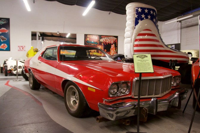 Red and white Ford Torino with Roller Skate hot rod in background.