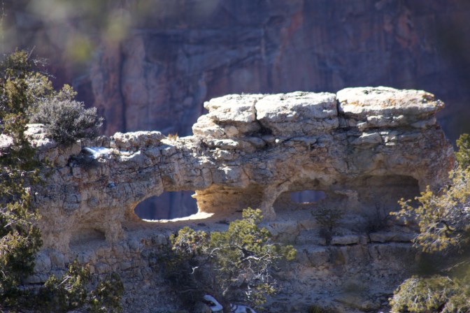 View of rocky formation with holes through the cliff.