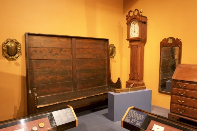 Collection of household goods including a grandfather clock, a high-backed bench, and a mirror.