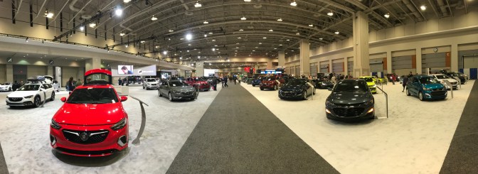 Panorama of interior of Washington Auto Show, with cars on left and right of a large central aisle.