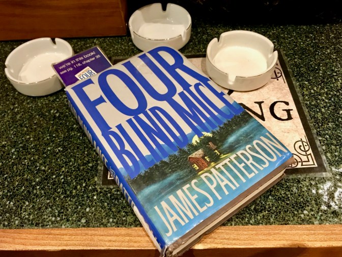 Copy of Four Blind Mice book by James Patterson, with three ashtrays in the background.