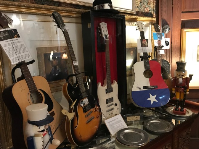 Five guitars on a sideboard, w with silver plates in the foreground.