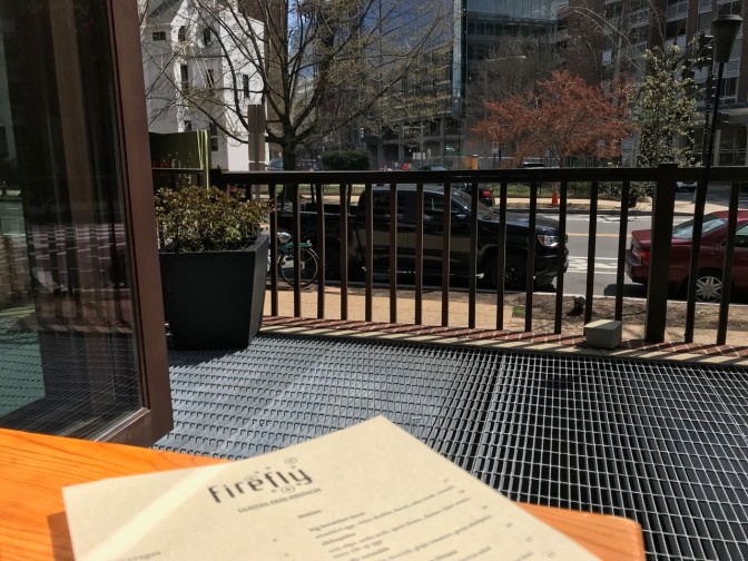 Firefly menu on table by open window, with street and buildings in view.