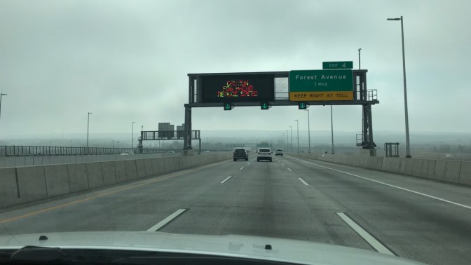 View of I-278 from behind dashboard of white Jeep Grand Cherokee. Sign says FOREST AVENUE 1 MILE EXIT 4. Other sign says CAUTION FOG AHEAD REDUCE SPEED.