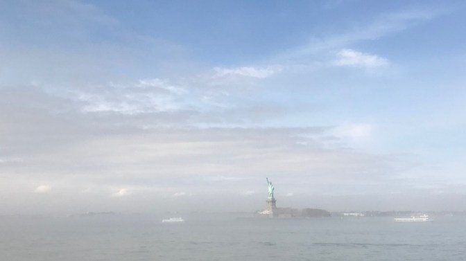 Statue of Liberty, with a layer of fog across the bay.