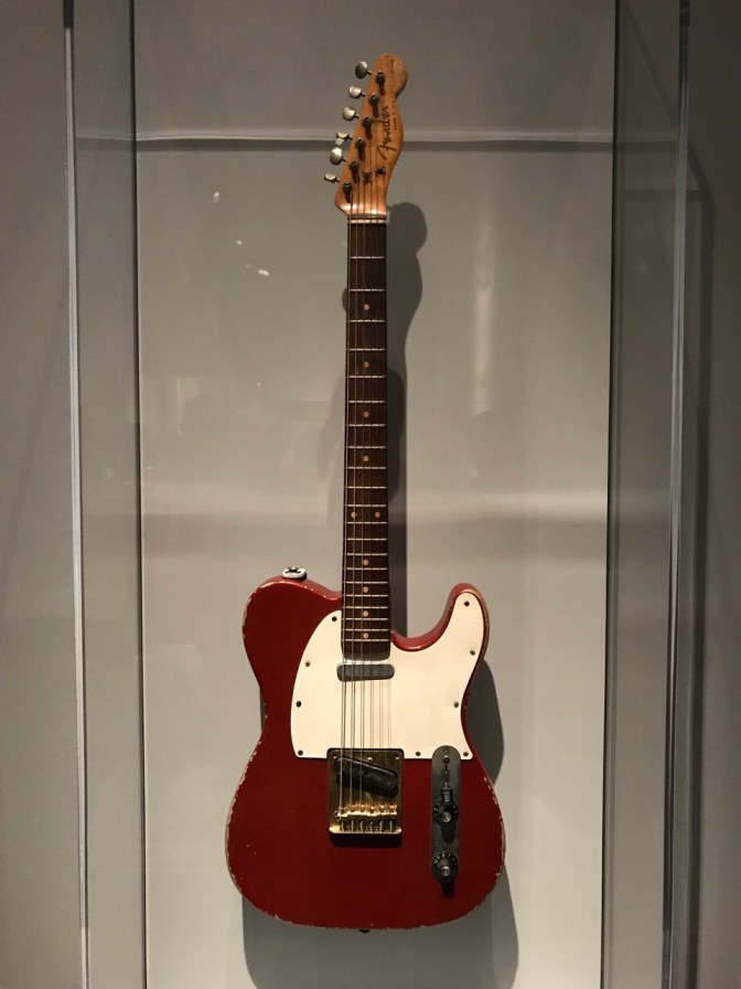Red Fender Telecaster with white pick guard.