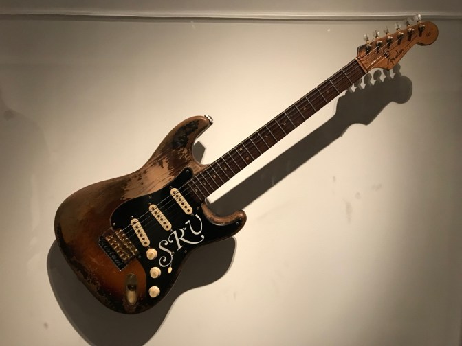 Fender Stratocaster, in raw wood, with the initials SRV in white on the black pick guard.