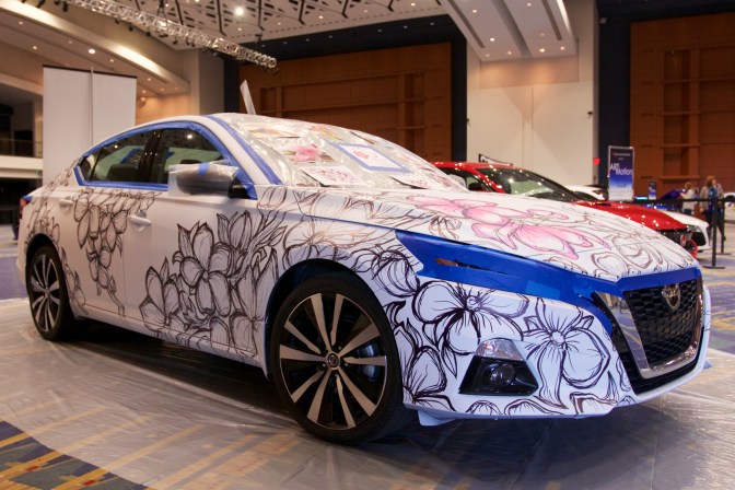 Nissan Altima painted with cherry blossoms. Painters tape covers the windows and headlights.