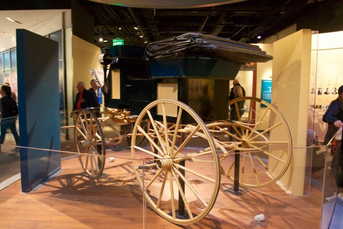 Horse-Drawn carriage, in black, with wooden wheels.