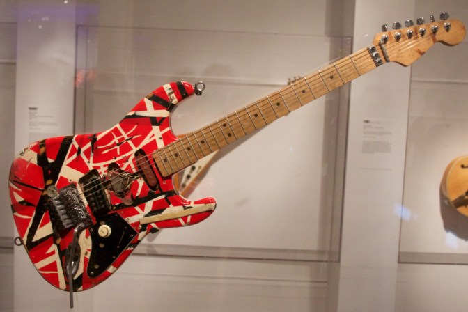 Red-White-Black Frankenstein stratocaster, hanging in clear display case.