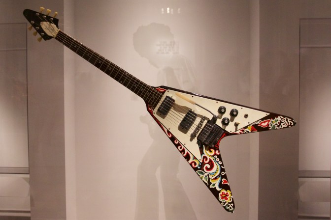 Gibson Flying V covered in psychedelic paint job. A silhouette of Jimi Hendrix is in the background.