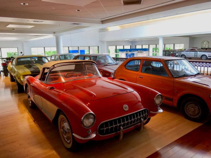 Red and white Chevrolet Corvette, with a yellow Camaro, an orange Honda Civic, and a red Honda Accord in the background.