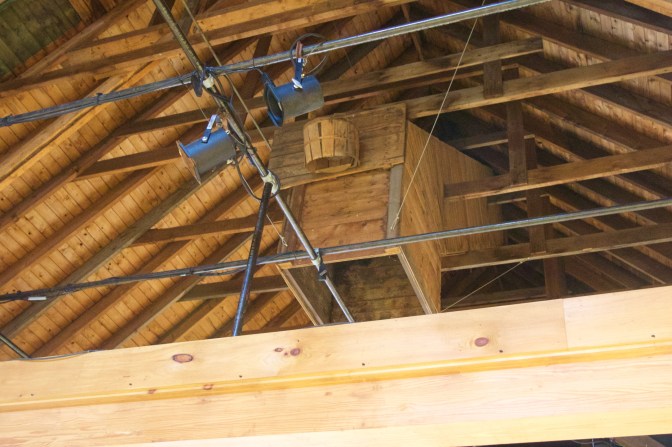 Basketball hoop made from wooden basket, in rafters of barn.