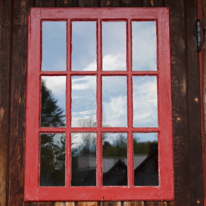 Close up of window on front of chalet, with red trim.