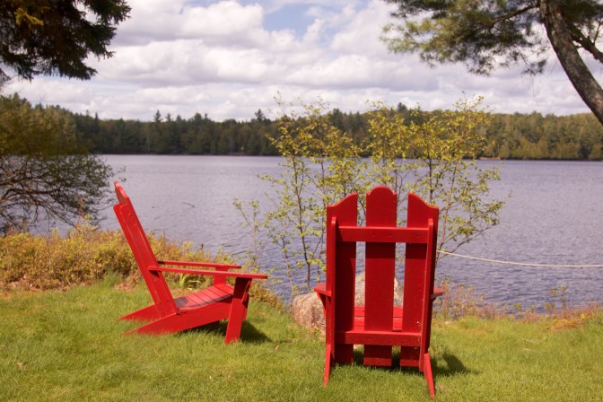 Red Adirondack Chairs by lakeside.