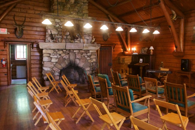 Interior of the playhouse, with wooden folding chairs in foreground and a large fireplace in the background. Several stuffed animal heads are mounted to the walls.