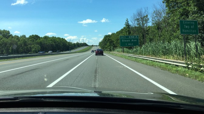 View of highway with signs along road that say ENTERING TWP OF HAMILTON and EXITS 65B-A SLOAN AVE 1 MILE