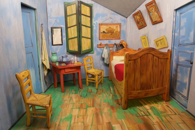 Sculpture of bedroom with bed, chairs, window, door, small table, and paintings.