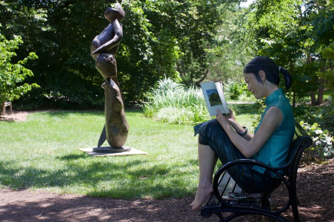 Sculpture of woman reading on a bench.