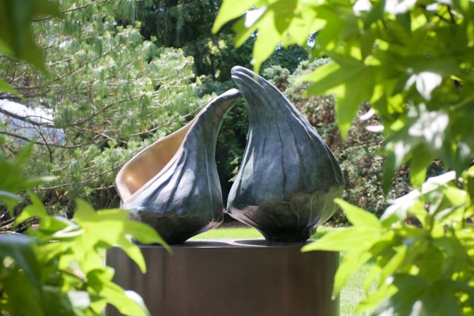 Two seashell bronze statues on a pedestal.