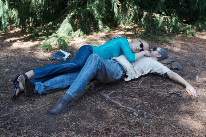Sculpture of man and woman napping on the ground.