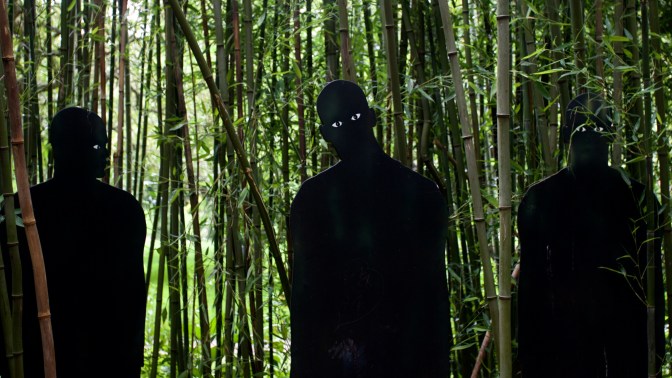 Three figures in silhouette, watching.