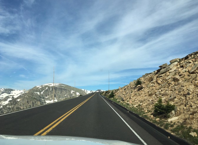 Road in mountains with wooden poles on either side of road.