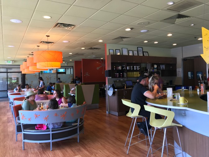 Interior of Snooze AM restaurant, with patrons dining at tables and counter.