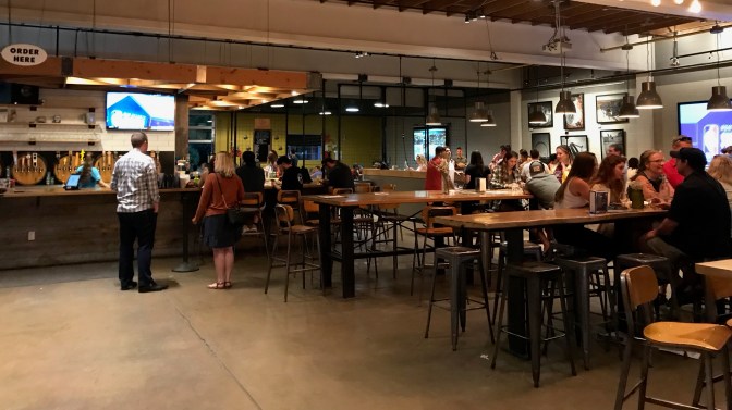 Interior of Rayback Collective with people eating and drinking at tables, and the bar in the background.