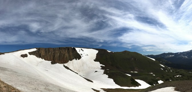Panorama of rocky mountainside covered in snow.