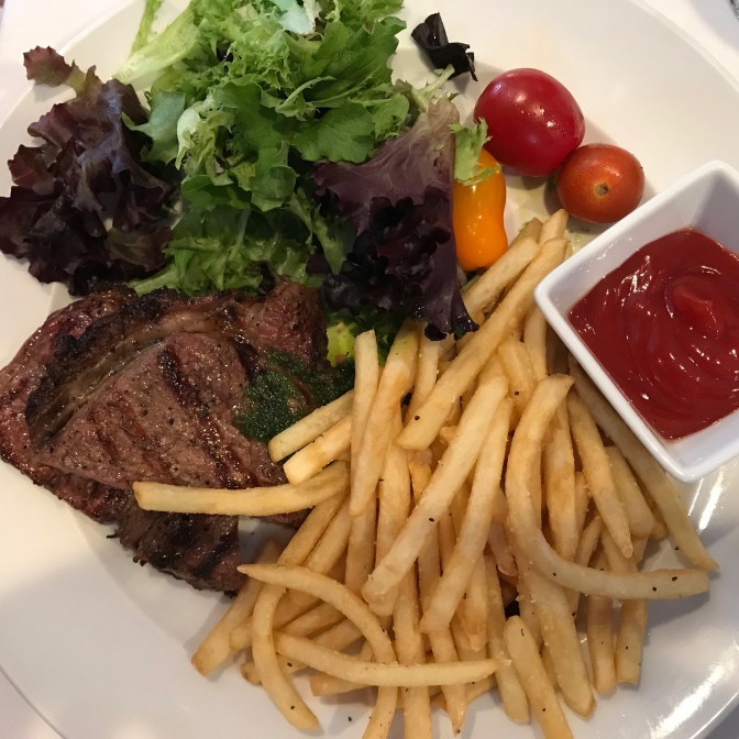 New York Strip Steak with french fries, ketchup, and greens.