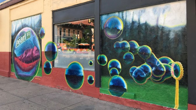 Wall mural of bubbles blowing from right to left. Leftmost bubble says PEARL STREET.