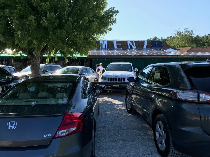 Exterior of Menz Restaurant with parking lot in foreground.