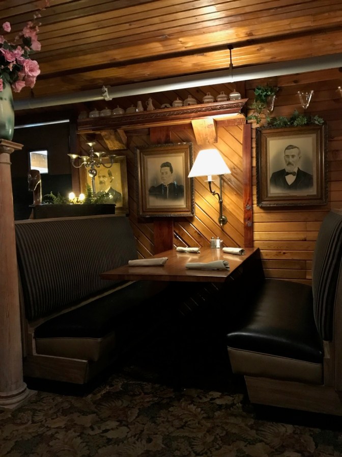 Booth seated for four, with two paintings hanging beside it, and bric-a-brac covering the walls.