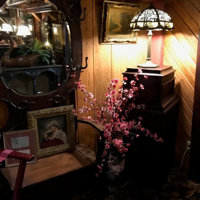 Chair, mirror, lamp, painting, and plant in vase in corner.