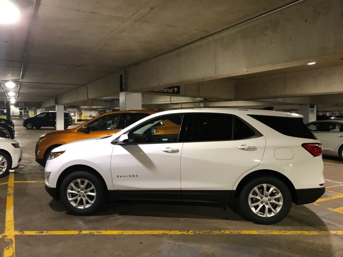White Chevrolet Equinox parked in parking garage.