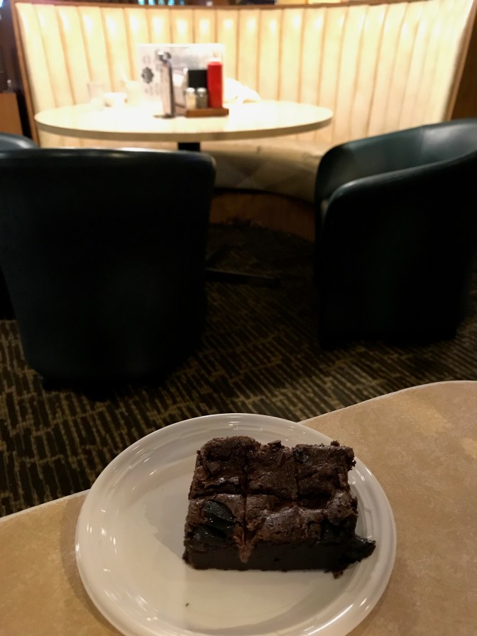 Brownie on plate on table, with empty booth in background.