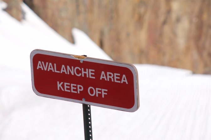 Red sign with white lettering that reads AVALANCHE AREA KEEP OFF