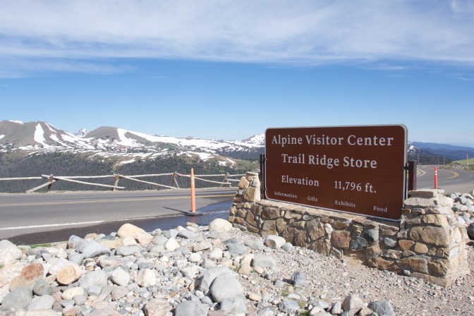 Road with sign that says ALPINE VISITOR CENTER TRAIL RIDGE STORE ELEVATION 11,796