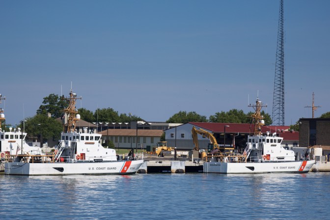 Two coast guard vessels tied at pier.