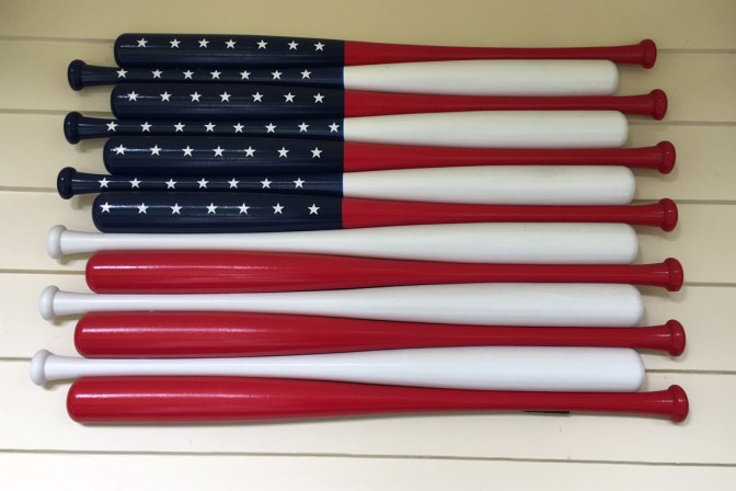 American flag made of baseball bats affixed to wall.