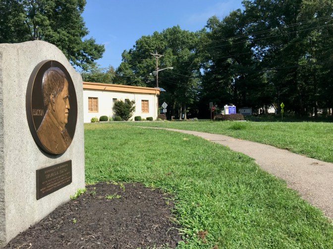 Relief of Edison on a marker, with museum in the background.