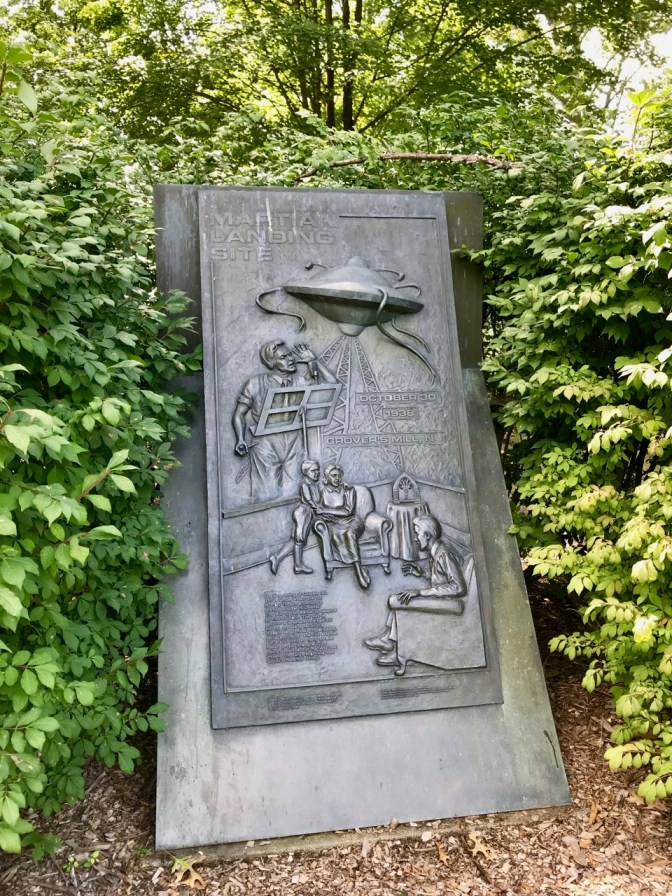 Bas relief plaque depicting Martian invasion, Orson Welles, and listeners at home.