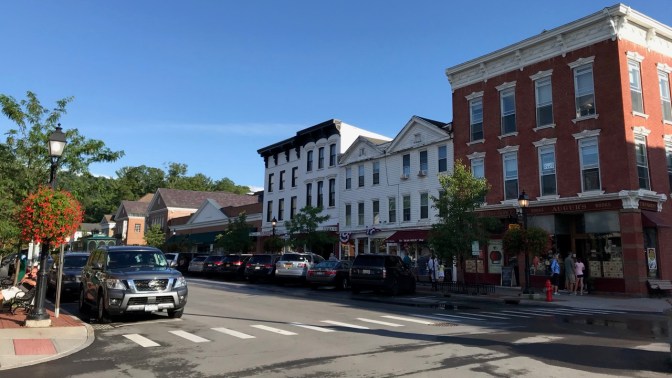 Main Street in Cooperstown with brick and wooden buildings across the street.