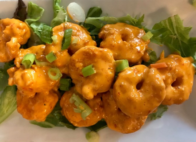 Bam Bam Shrimp in sauce, over bed of greens.