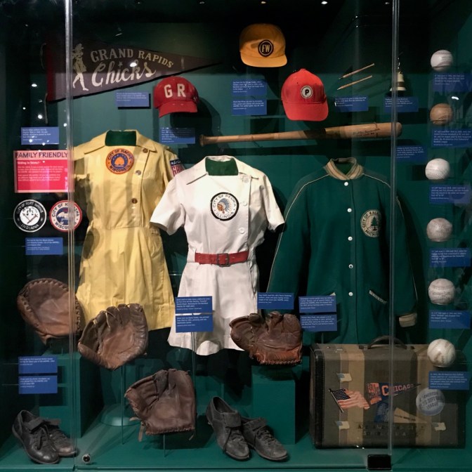 Display of women in baseball, including informs, caps, balls, and bats.