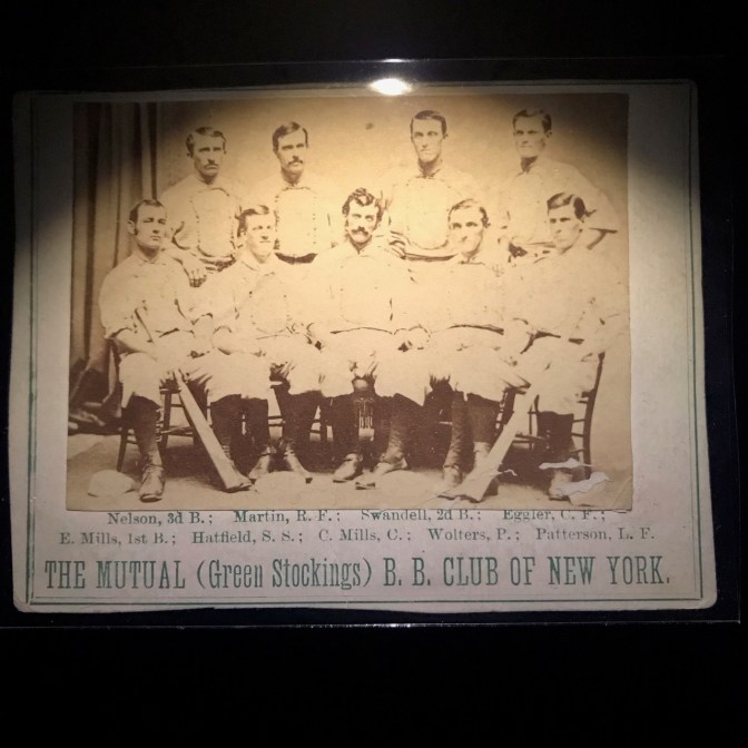 1871 baseball card with 9 players on it and words saying THE MUTUAL GREEN STOCKINGS B.B. CLUB OF NEW YORK.