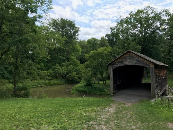Hyde Hall covered bridge, with a forest behind it.